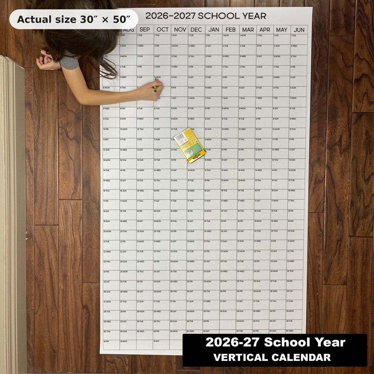 Child writing on the 2026-27 School Year giant wall calendar on the floor, showing its real 30 x 50 inch size