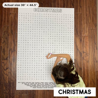 Thumbnail for Child doing the Christmas giant word search on the floor, showing its real 30 x 44.5 inch size
