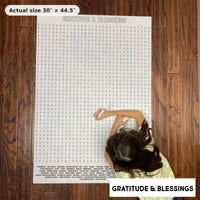 Thumbnail for Child doing the Gratitude & Blessings giant word search on the floor, showing its real 30 x 44.5 inch size