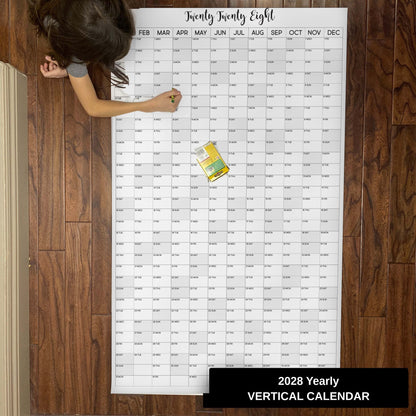 Child writing on the 2028 yearly vertical giant paper wall calendar on a wood floor