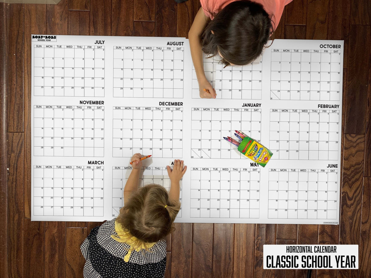 Child writing on the 2027-28 Classic School Year horizontal giant paper wall calendar on a wood floor
