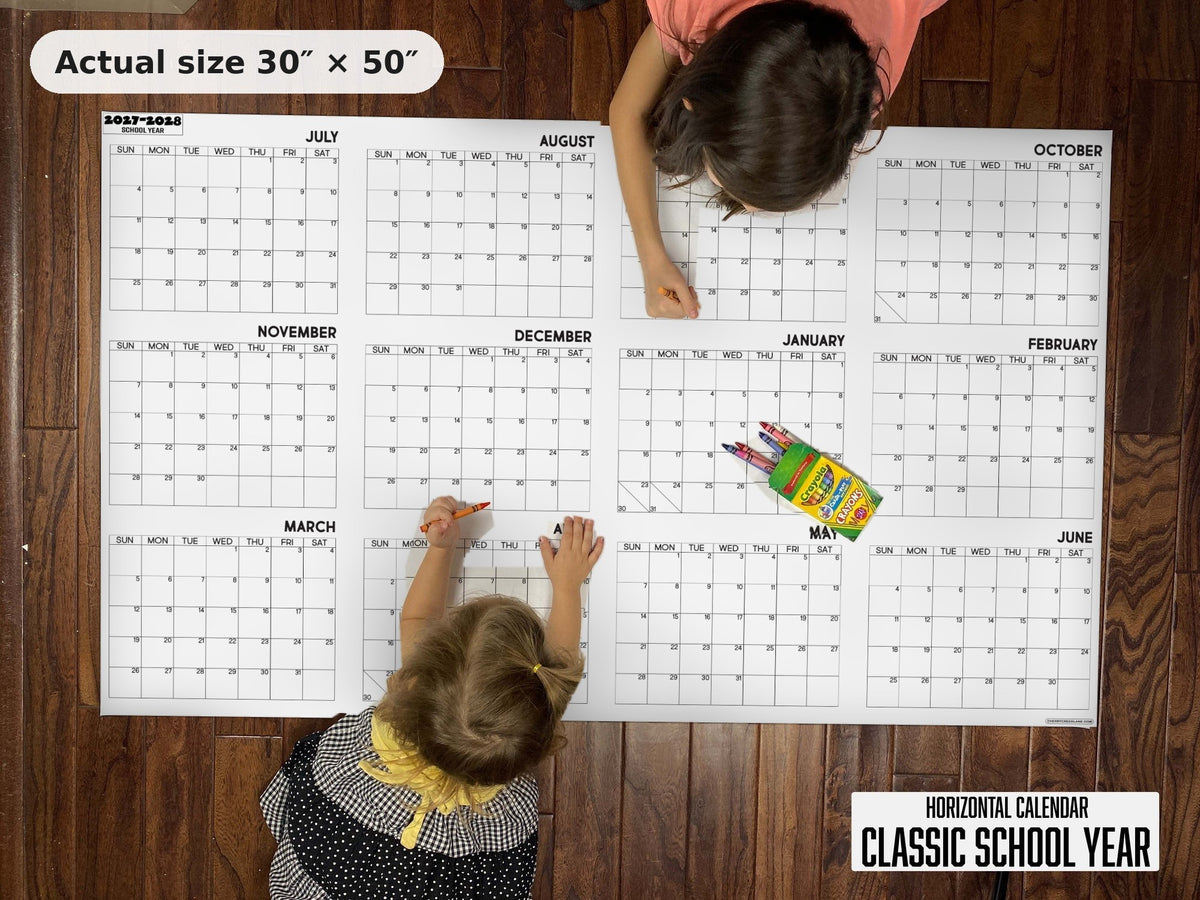Two kids writing on the Classic School Year giant calendar on the floor, showing its real 30 x 50 inch size
