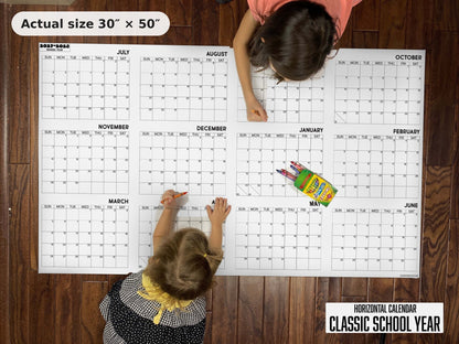 Two kids writing on the Classic School Year giant calendar on the floor, showing its real 30 x 50 inch size