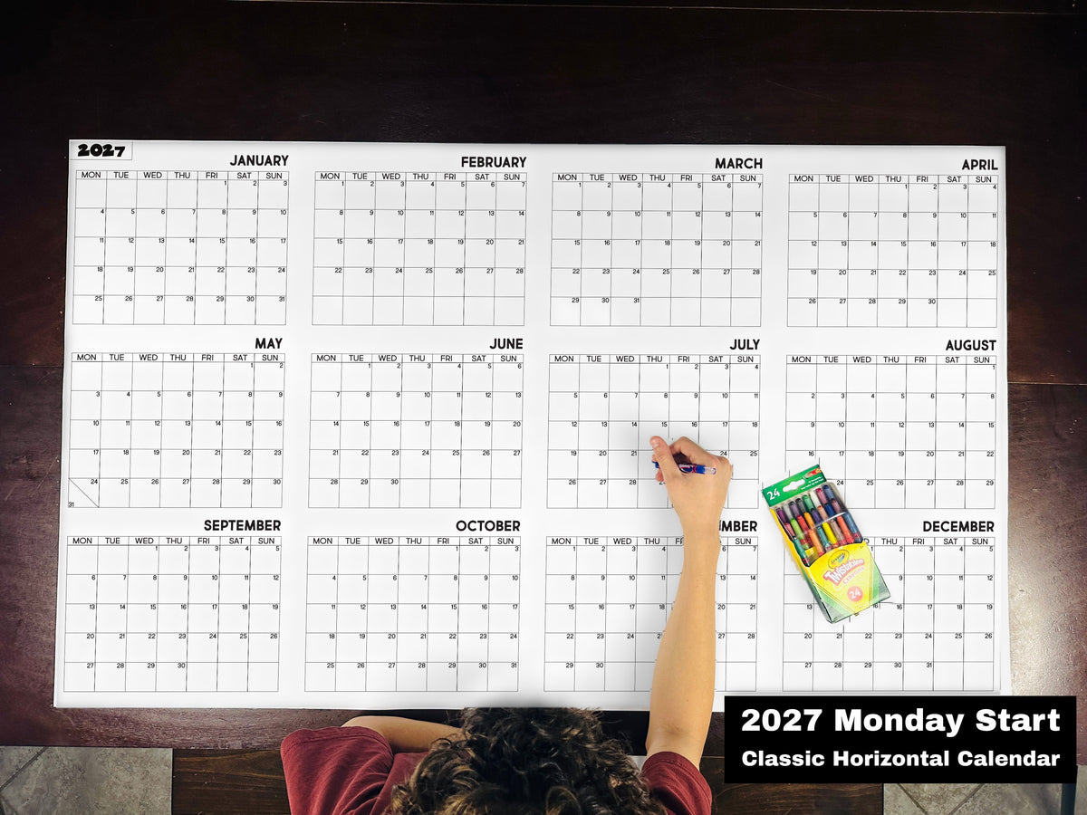 Child coloring the 2027 Monday start classic horizontal yearly calendar on a table