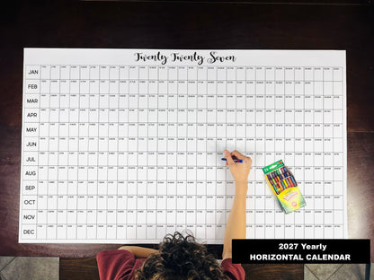 Child writing on the 2027 yearly horizontal giant paper wall calendar on a wood floor