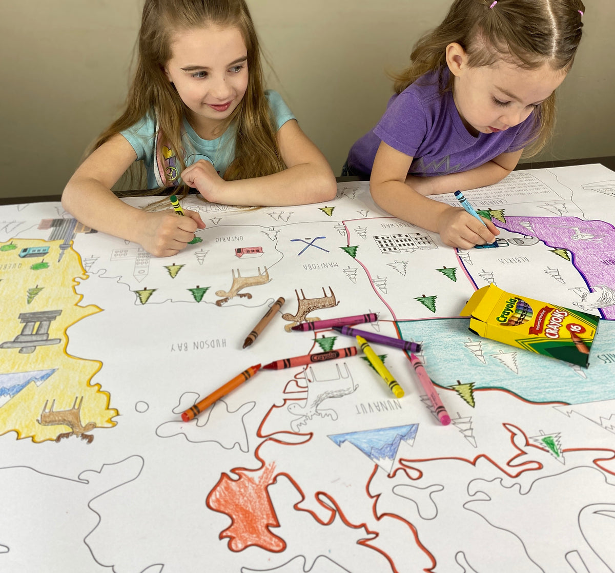 The Canada giant coloring map being colored in with markers at a table