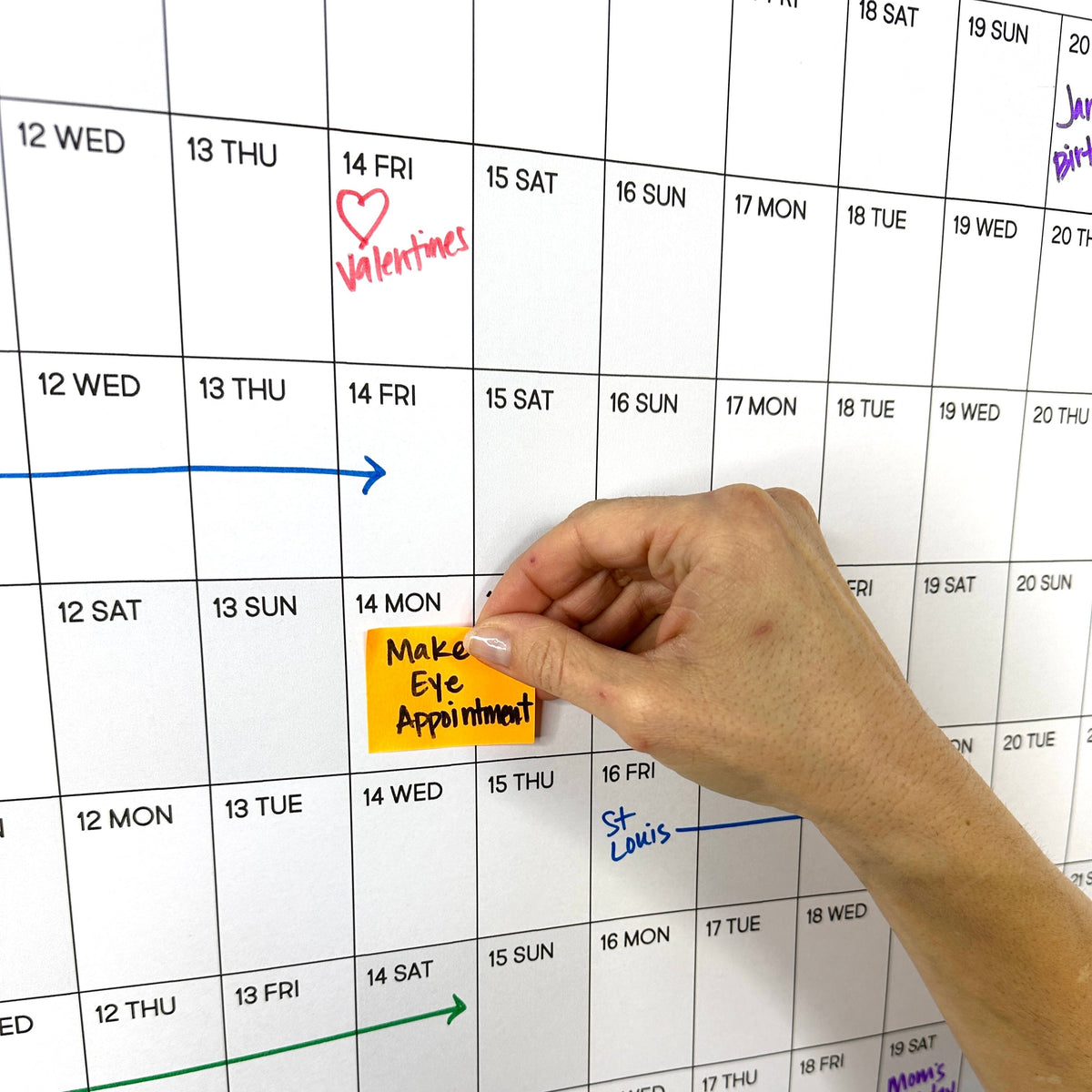 Close-up of a hand writing plans on the 2027 Yearly giant paper calendar