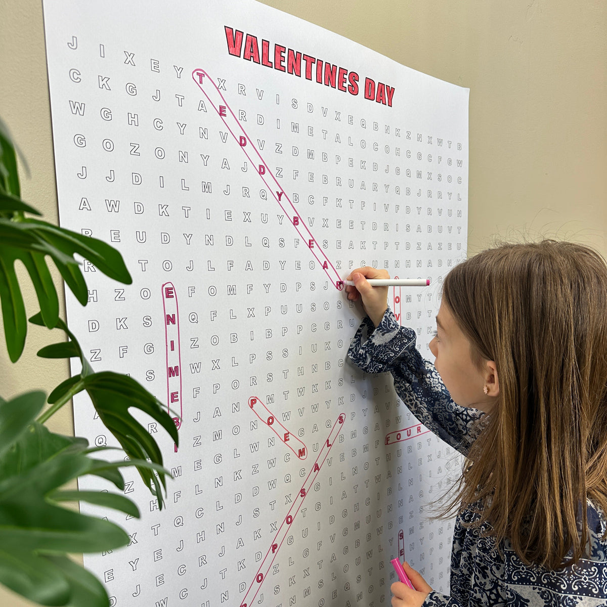 Kids circling words on the Valentines Day giant word search hung on a wall