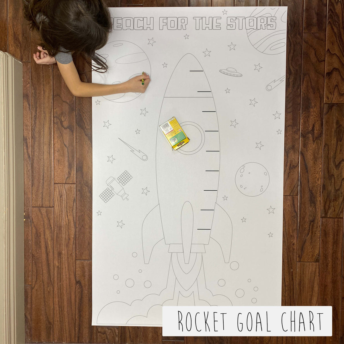Child coloring the Rocket Goals Chart giant coloring sheet on a wood floor with crayons