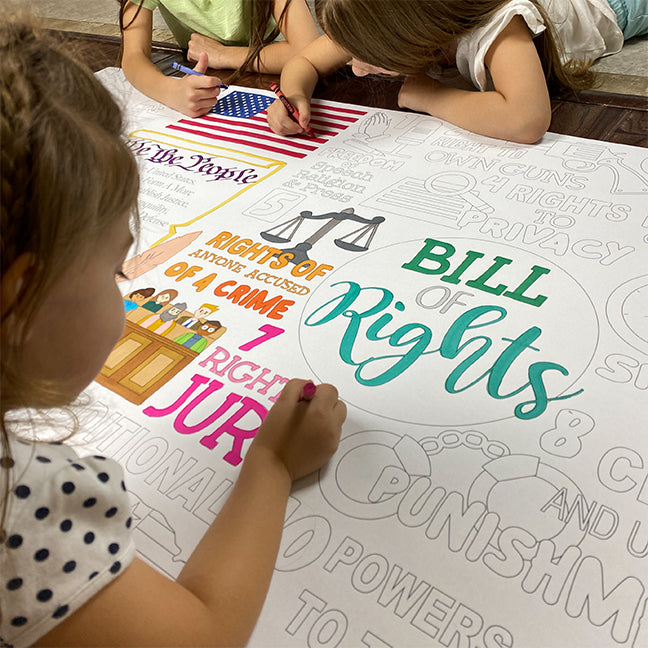 The We the People giant coloring sheet being colored in with markers at a table
