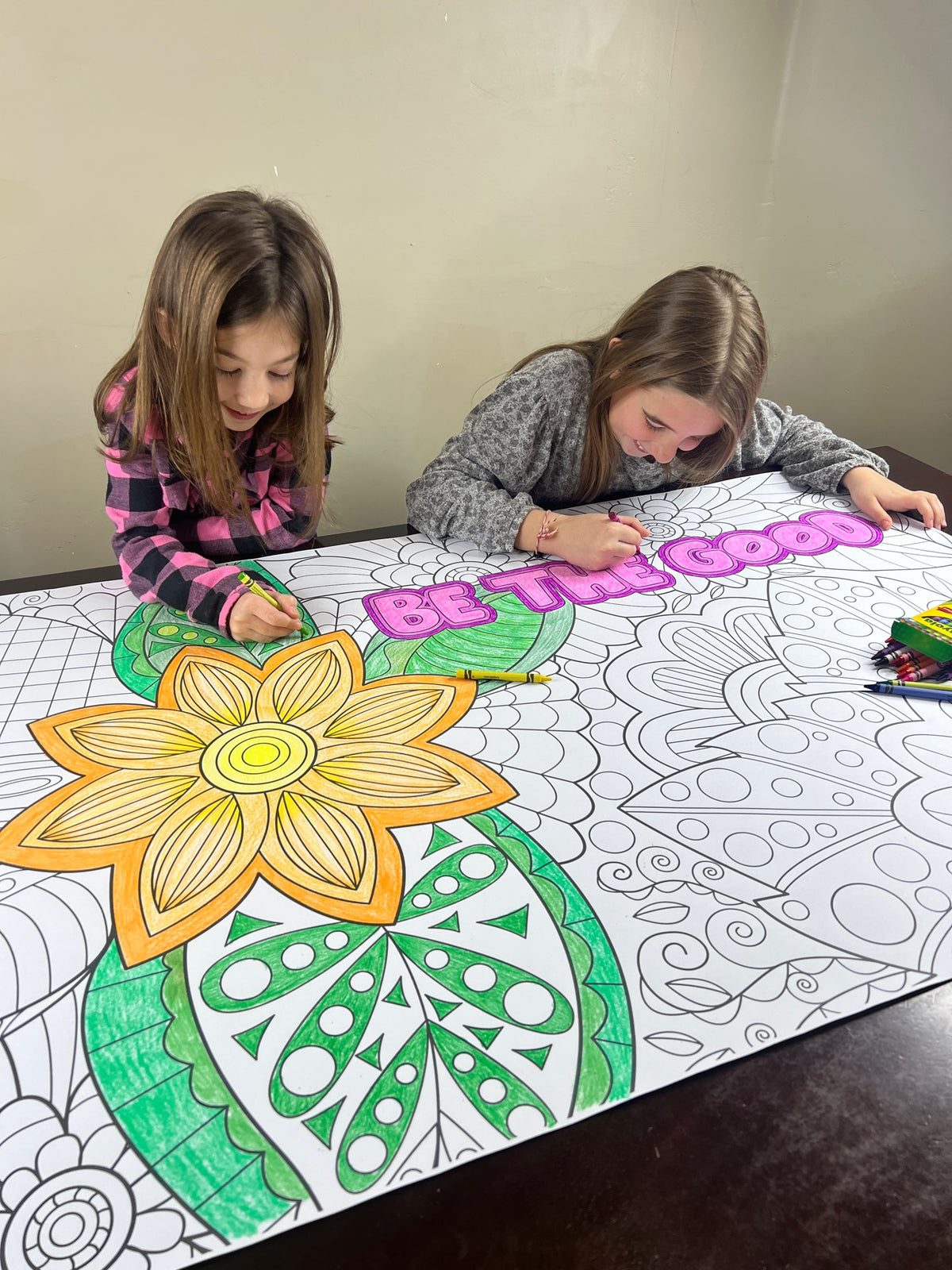 The Zentangle Be The Good giant coloring sheet being colored in with markers at a table