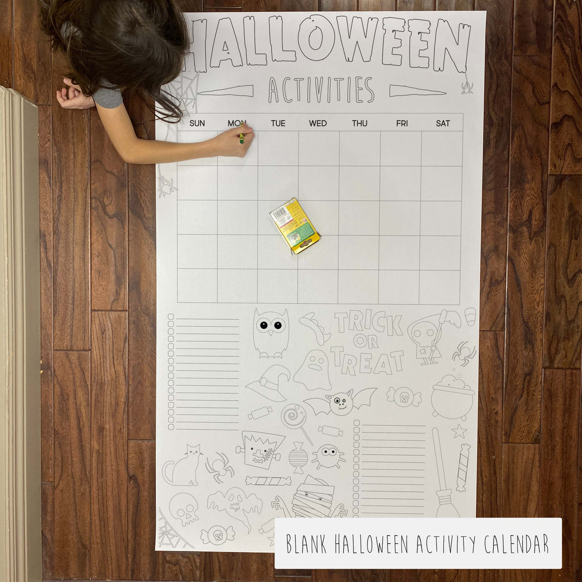 Child coloring the blank Halloween Activity Calendar giant coloring sheet on a wood floor