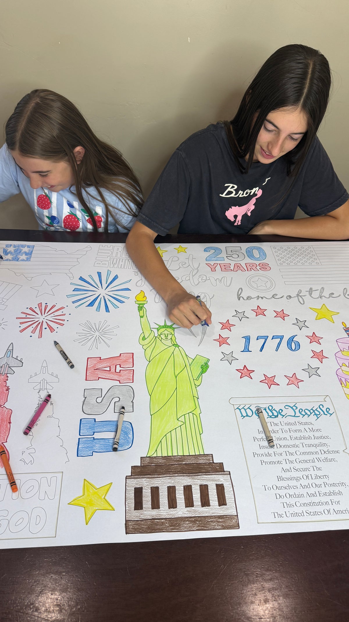 The America 250 giant coloring sheet being colored in with markers at a table