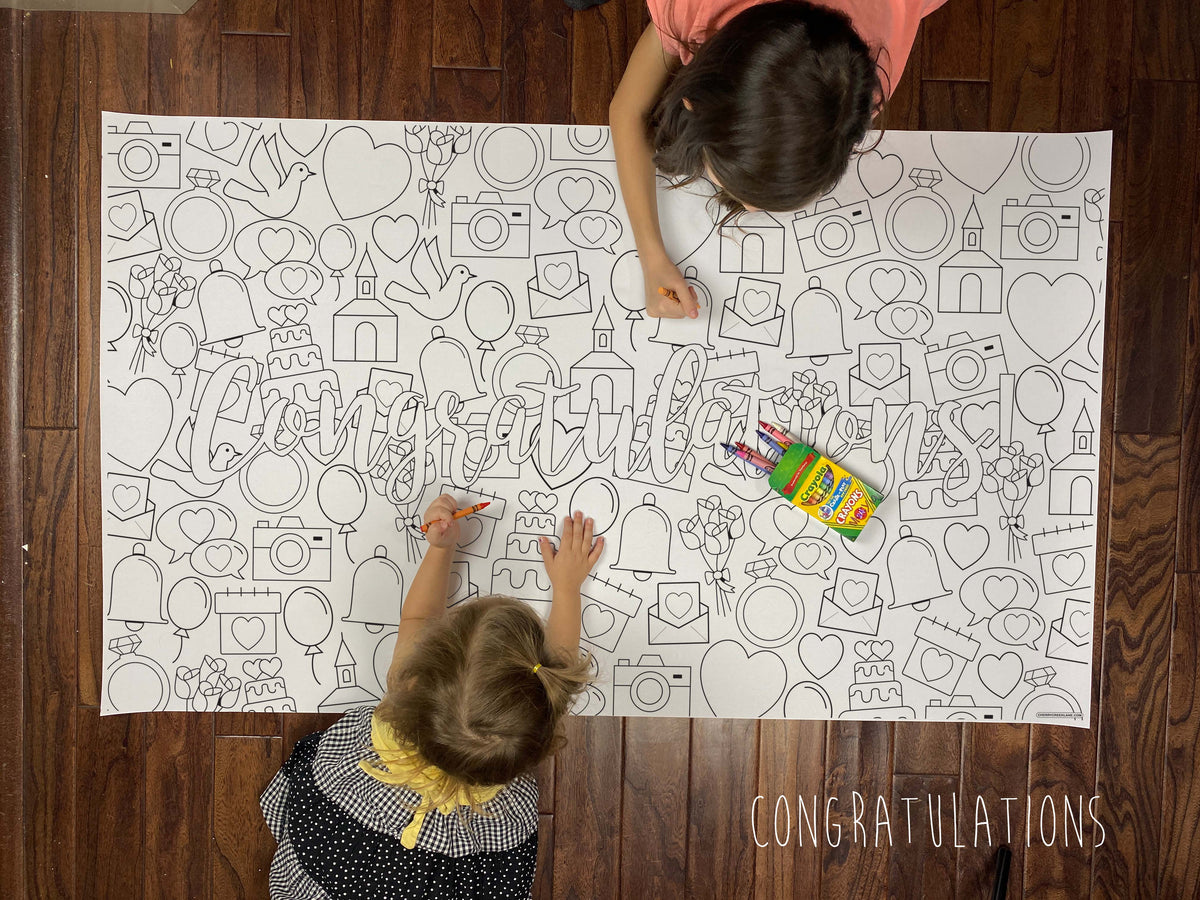 Child coloring the Congratulations giant coloring sheet on a wood floor with crayons