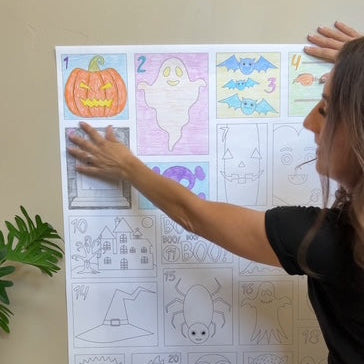 Woman pointing at the Halloween Countdown calendar coloring sheet hung on a wall
