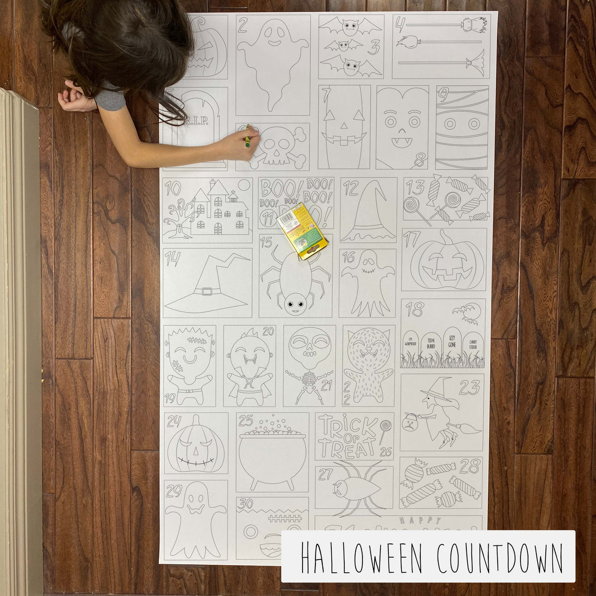 Child coloring the Halloween Countdown Calendar giant coloring sheet on a wood floor