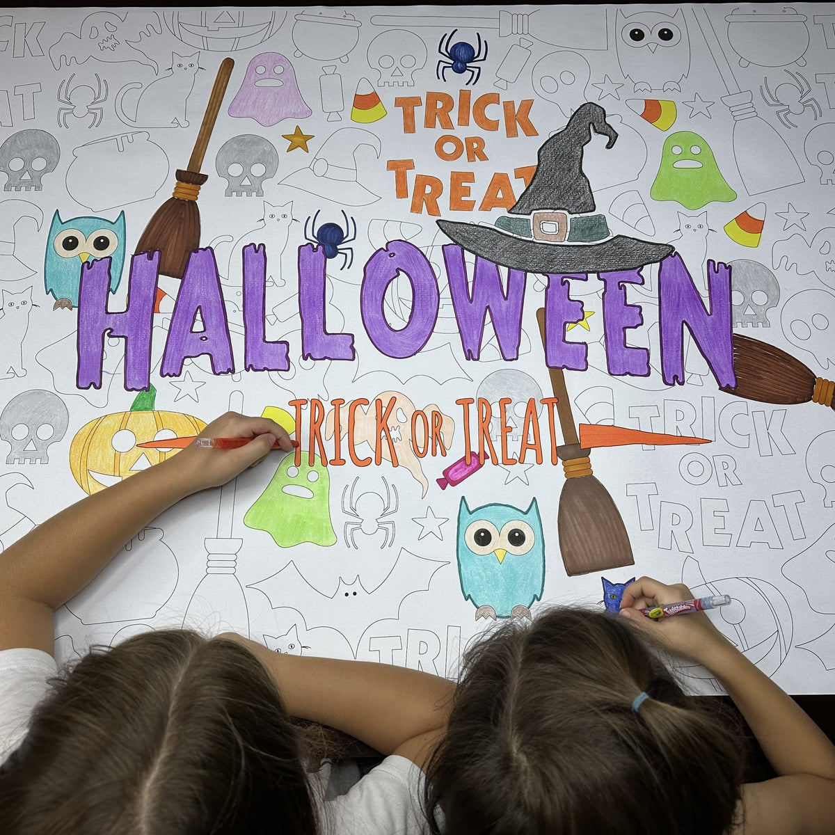 The Happy Halloween Table Size Coloring Sheet being colored by kids at home