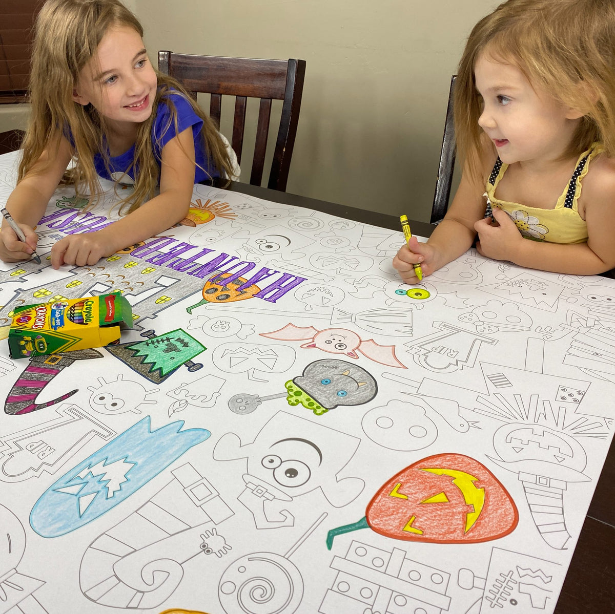The Haunted House giant coloring sheet being colored in with markers at a table
