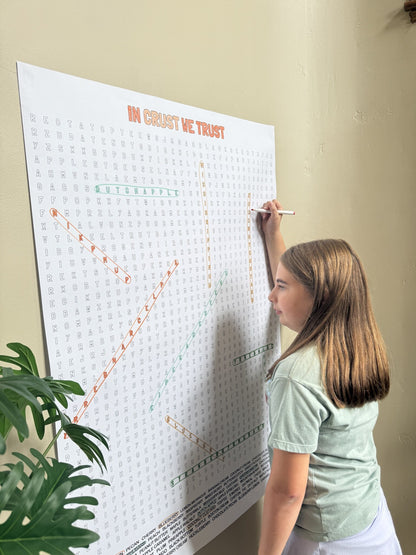 Girl circling words on the In Crust We Trust Giant Word Search Puzzle, a giant 30x44.5 inch sheet on the wall