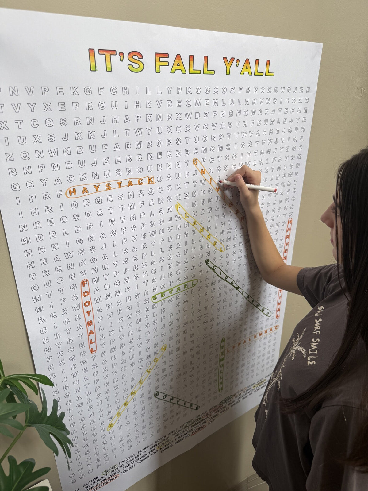 Girl circling words on the It's Fall Y'all Giant Word Search Puzzle, a giant 30x44.5 inch sheet on the wall