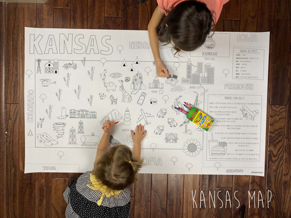 Child coloring the Kansas state giant coloring map on a wood floor