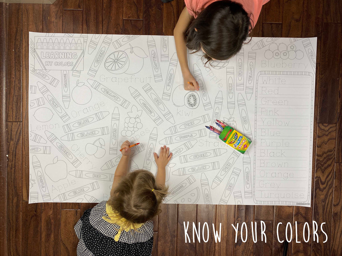 Child coloring the Know Your Colors giant coloring sheet on a wood floor with crayons