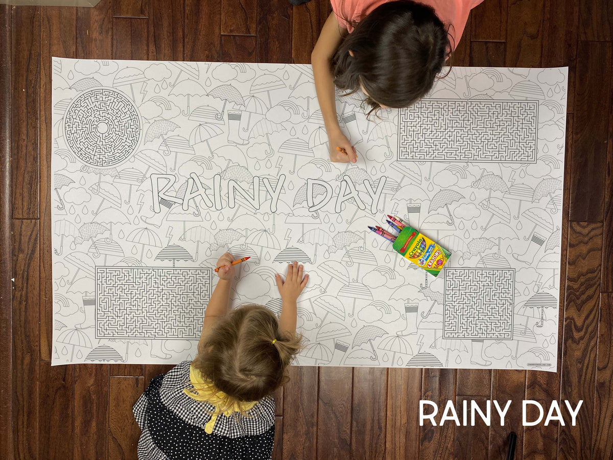 Child coloring the Rainy Day giant coloring sheet on a wood floor with crayons