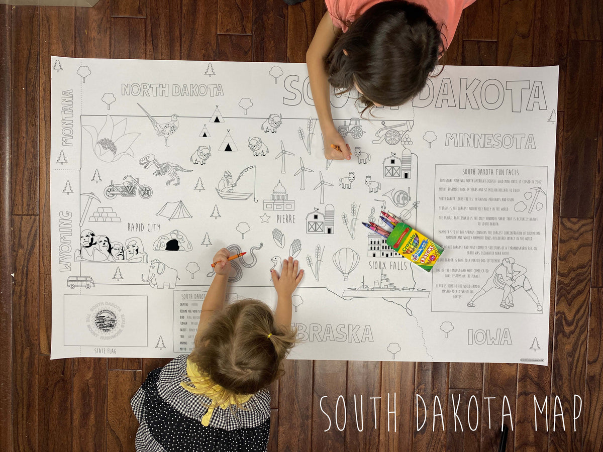 Child coloring the South Dakota state giant coloring map on a wood floor