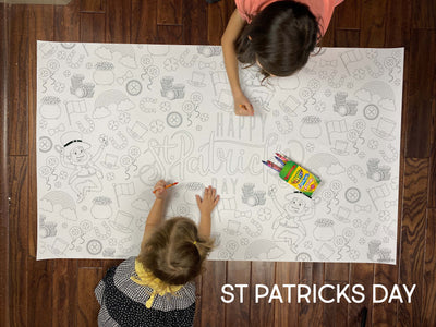 Child coloring the St Patricks giant coloring sheet on a wood floor with crayons