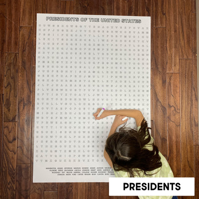 Child solving the USA Presidents giant word search poster on a wood floor