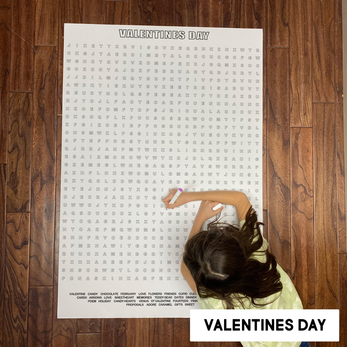 Child solving the Valentines Day giant word search poster on a wood floor