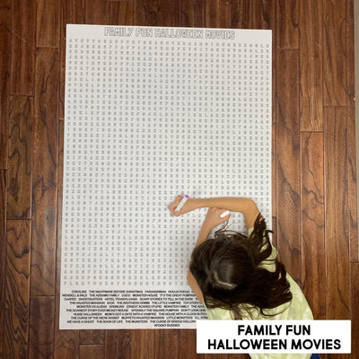 Child solving the Family Halloween Movies giant word search poster on a wood floor