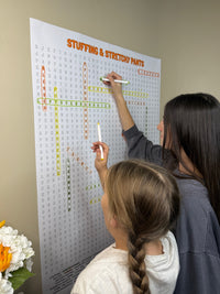 Thumbnail for Kids circling words on the Stuffing & Stretchy Pants giant word search hung on a wall