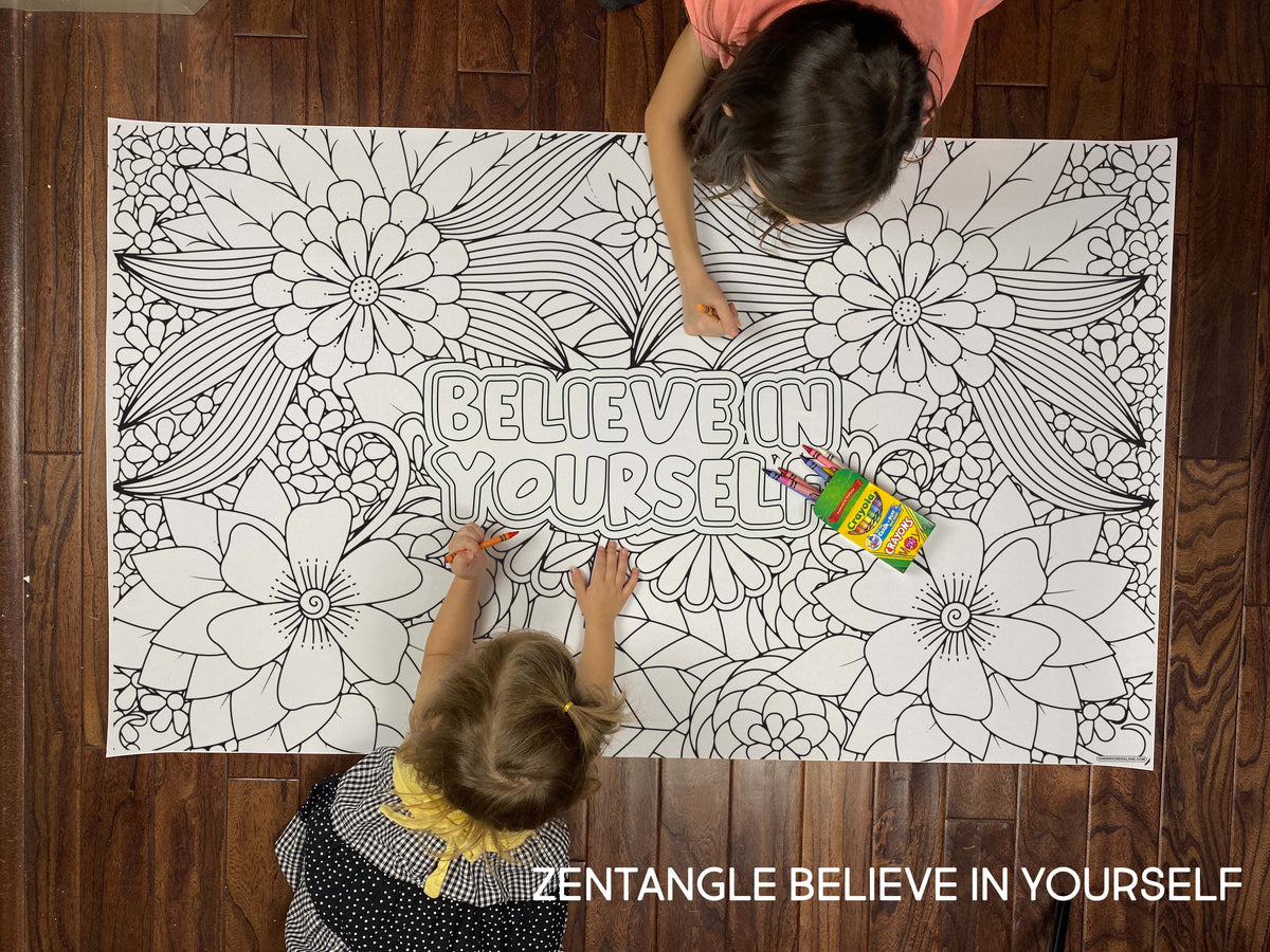 Child coloring the Zentangle Believe In Yourself giant coloring sheet on a wood floor with crayons