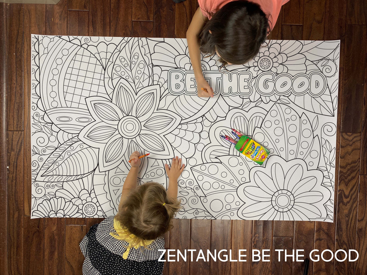 Child coloring the Zentangle Be The Good giant coloring sheet on a wood floor with crayons