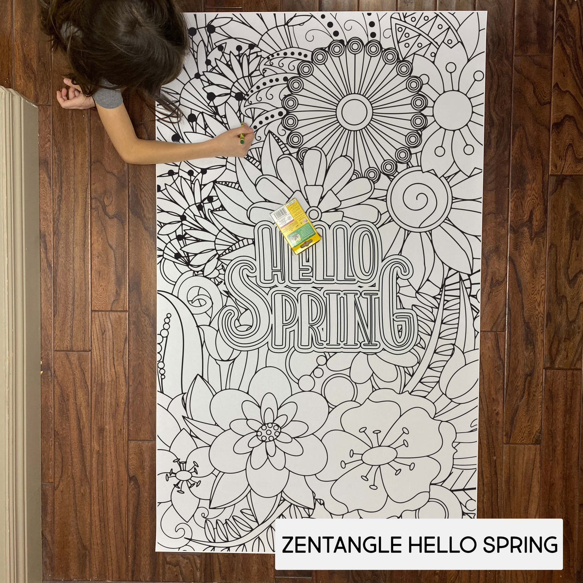 Child coloring the Zentangle Hello Spring giant coloring sheet on a wood floor with crayons