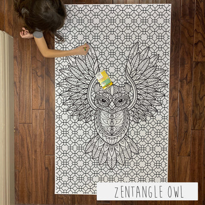Child coloring the Zentangle Owl giant coloring sheet on a wood floor with crayons