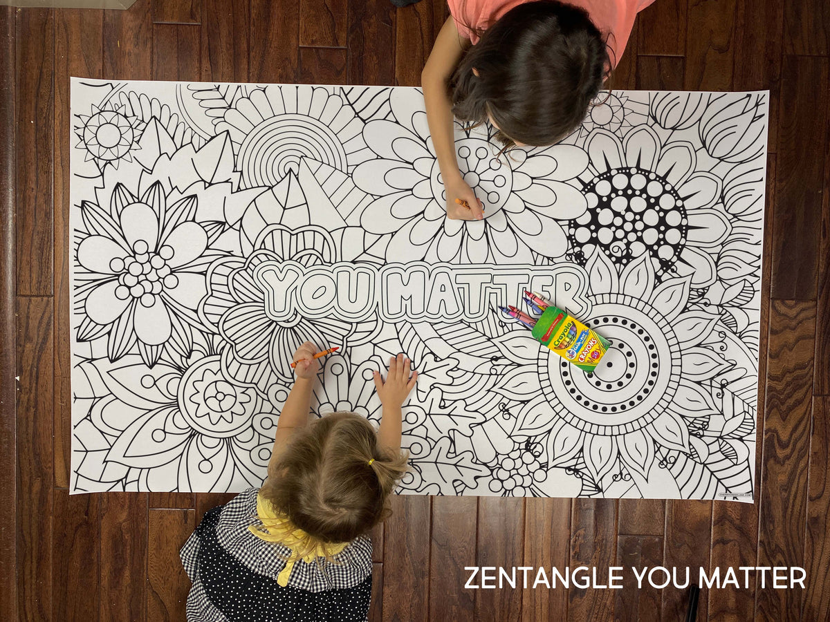 Child coloring the Zentangle You Matter giant coloring sheet on a wood floor with crayons