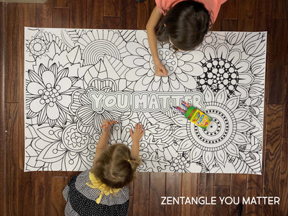 Child coloring the Zentangle You Matter giant coloring sheet on a wood floor with crayons