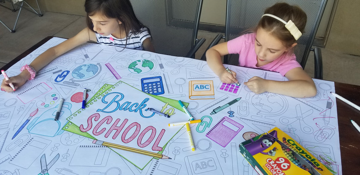 The Back To School giant coloring sheet being colored in with markers at a table