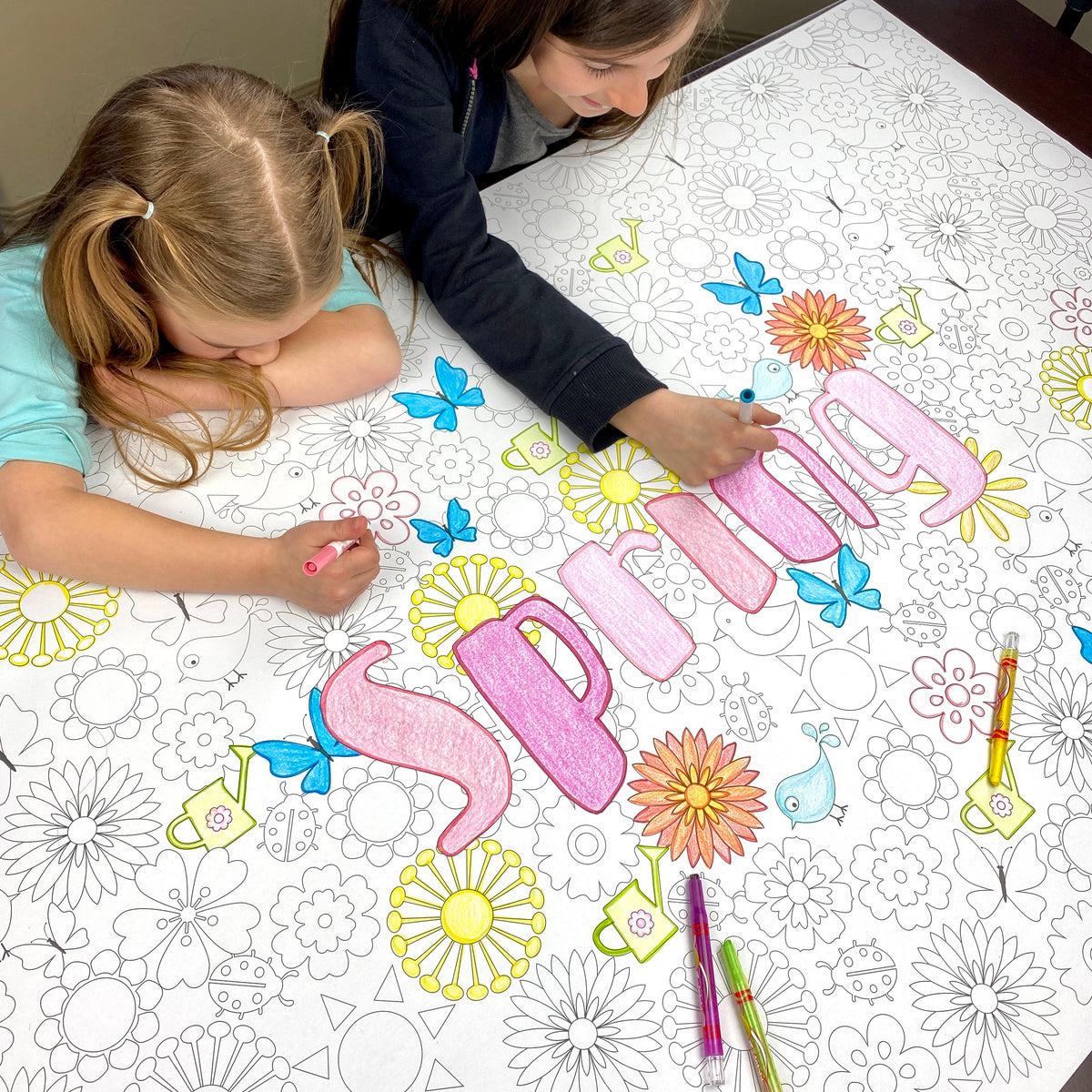 The Spring giant coloring sheet being colored in with markers at a table