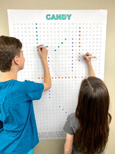 Kids circling words on the Candy giant word search hung on a wall