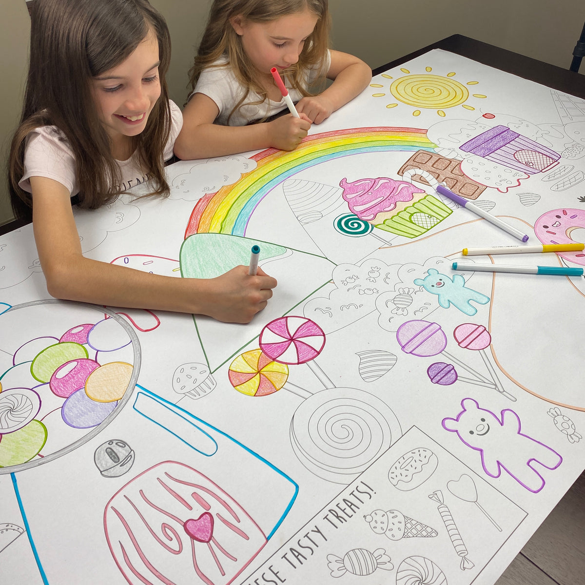 A candy themed giant coloring sheet being colored in with markers at a table