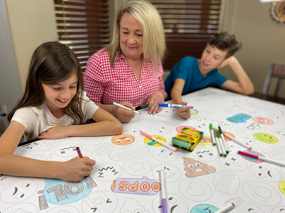 The Emoji giant coloring sheet being colored in with markers at a table