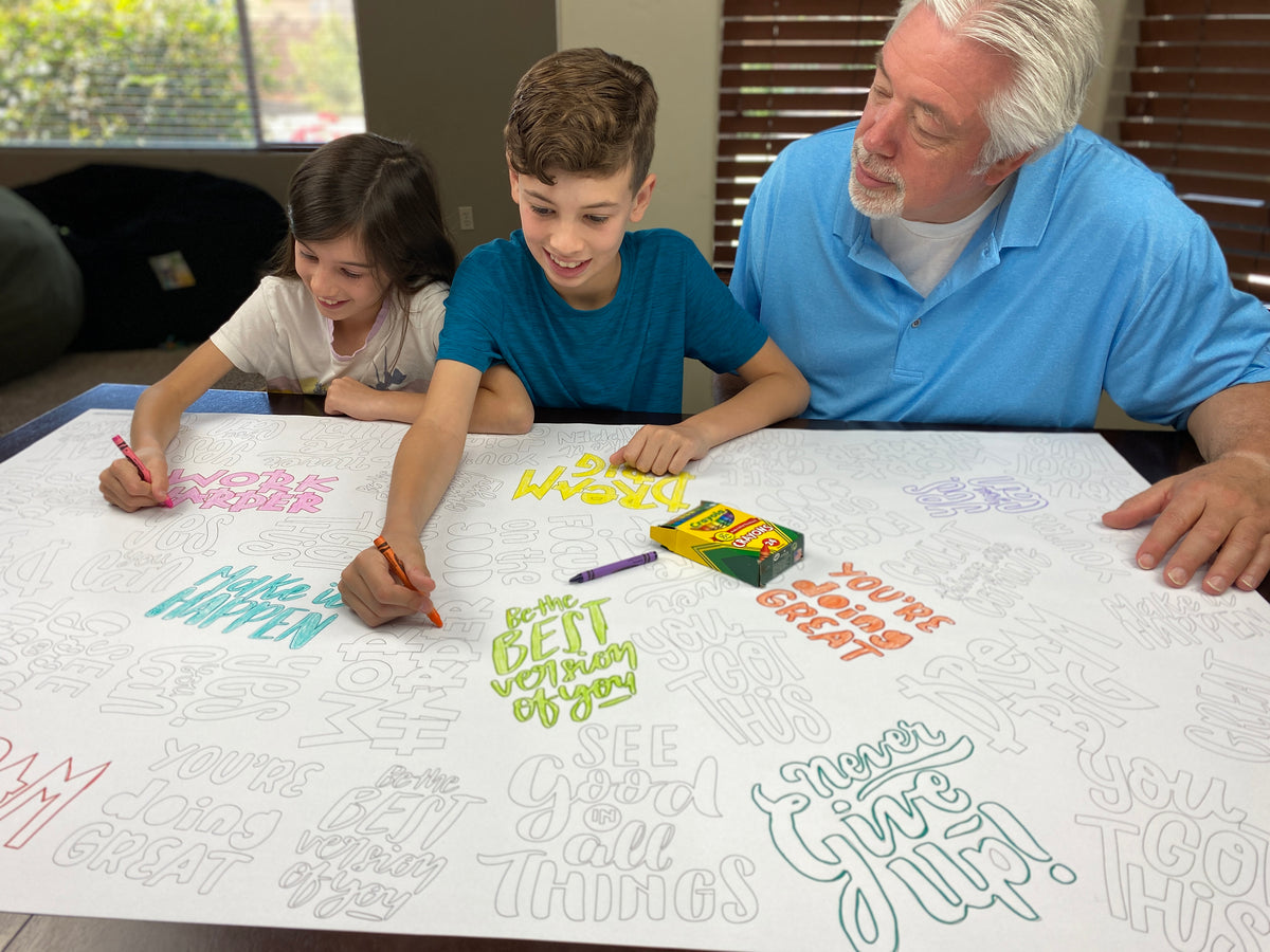 The Motivation Quotes giant coloring sheet being colored in with markers at a table