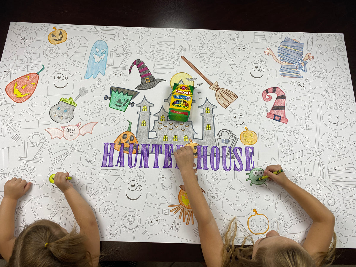 The Haunted House giant coloring sheet being colored in with markers at a table
