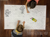 Thumbnail for Child coloring the Thanksgiving 4-up giant coloring sheet on a wood floor with crayons