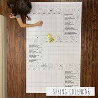 Thumbnail for Child coloring the Spring Activity Calendar giant coloring sheet on a wood floor
