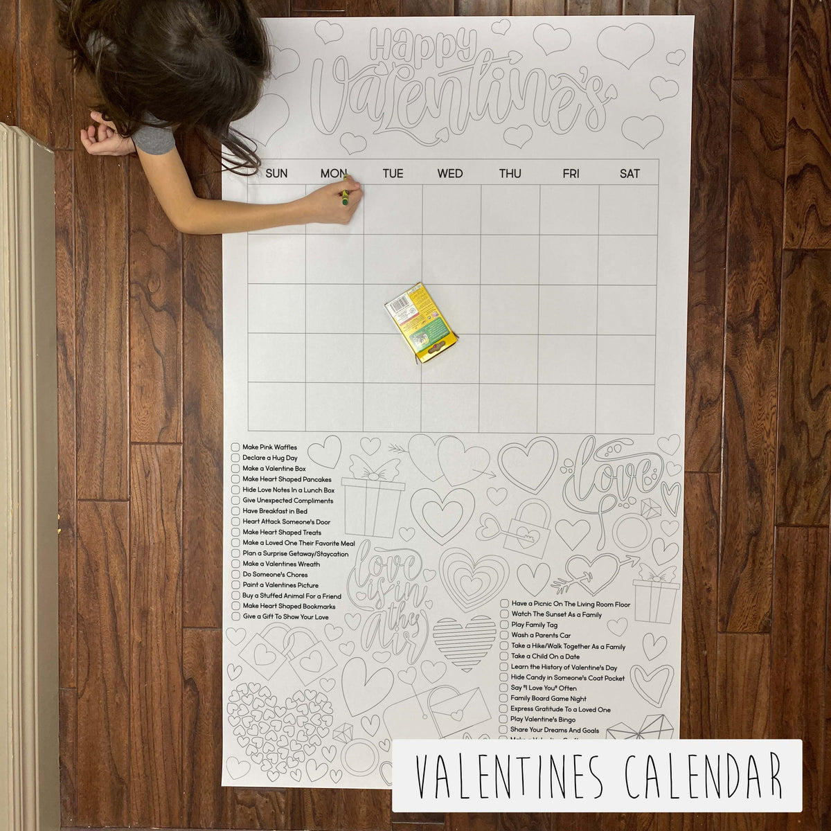 Child coloring the Valentines Activity Calendar giant coloring sheet on a wood floor
