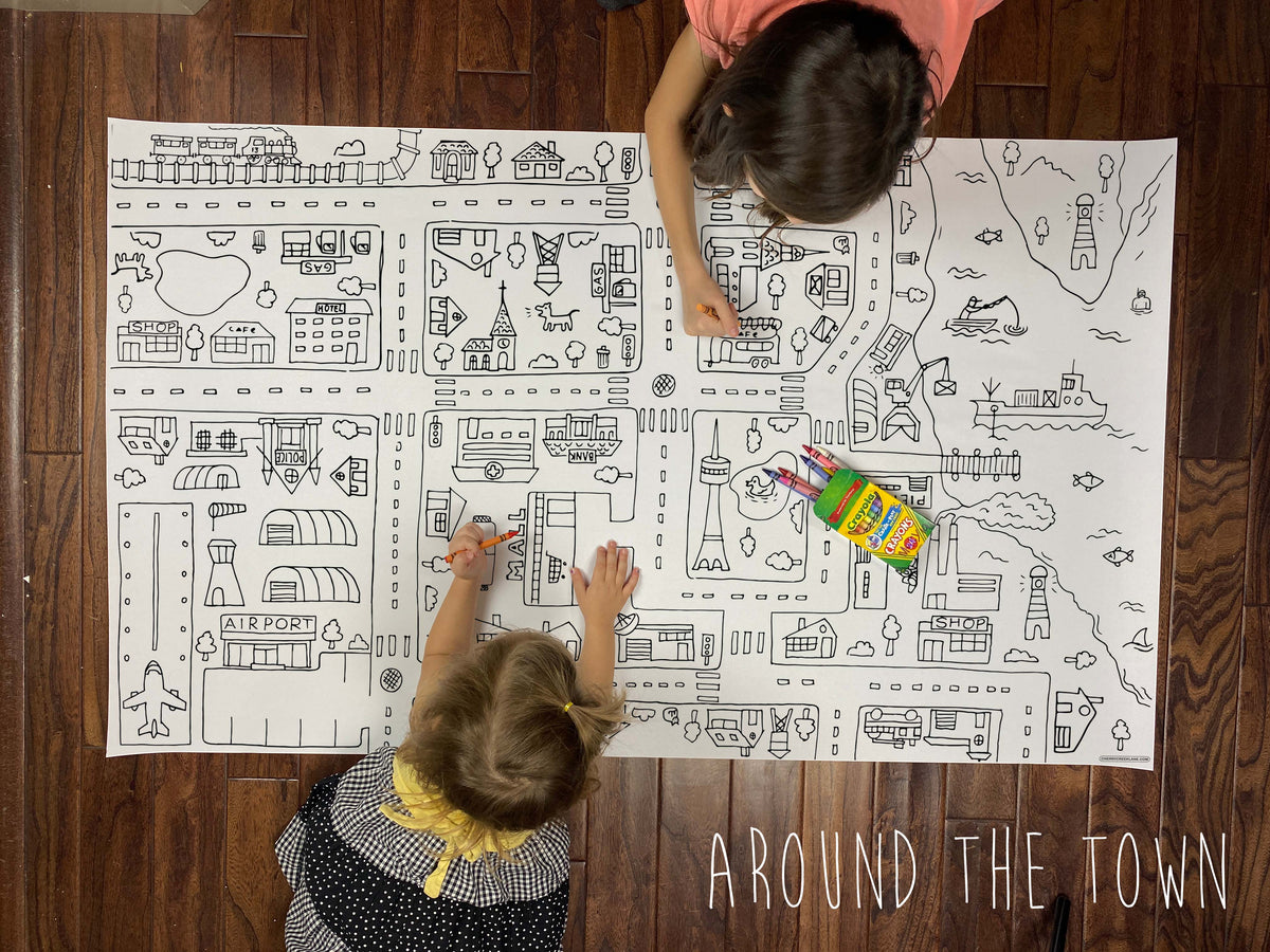Child coloring the Around The Town giant coloring sheet on a wood floor with crayons